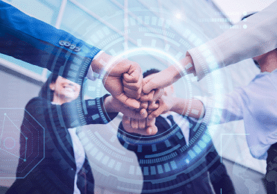 A group of diverse business professionals join their fists together in a gesture of unity and teamwork. The background includes a futuristic, transparent overlay with digital interface elements, suggesting themes of technology and collaboration in industries like aluminium Schmiedeteile Herstellung.