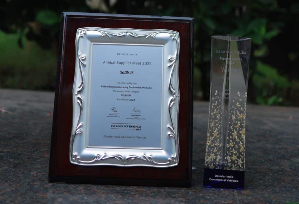 Eine gerahmte Preistafel und eine transparente Trophäe mit goldenen Sternen, beide von Daimler India Commercial Vehicles gestiftet, sind auf einer Steinfläche im Freien ausgestellt.