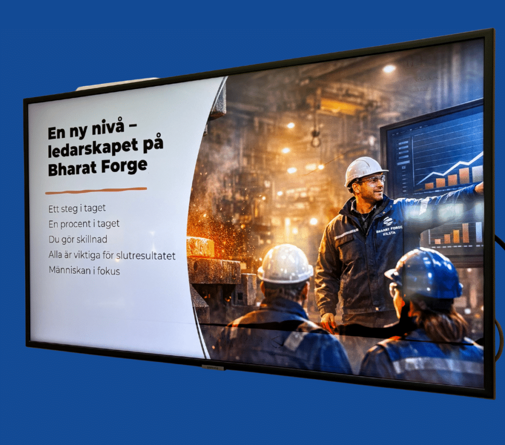 Eine Präsentationsfolie auf einem Bildschirm zeigt Arbeiter in Sicherheitsausrüstung auf einem Industriegelände. Der schwedische Text behandelt die Führung bei Bharat Forge und konzentriert sich auf Teamarbeit, Fortschritt und Menschen.